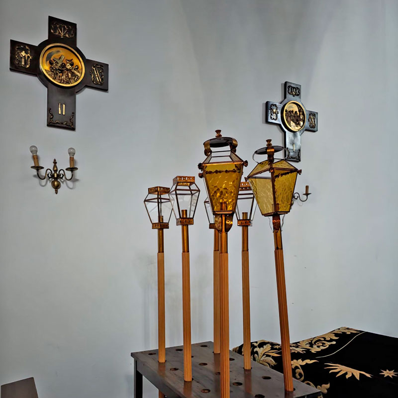 Conjunto de faroles artesanales de cristal y metal utilizados en procesiones de Semana Santa, colocados sobre soporte de madera.